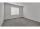 A simple bedroom featuring neutral carpet, white walls, and a large window at 4448 Mahogany Hills Ave, Las Vegas, NV 89141