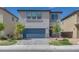 Two-story home with a blue garage door and charming landscaping at 4448 Mahogany Hills Ave, Las Vegas, NV 89141