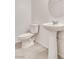 Powder room featuring white pedestal sink and toilet, complemented by a round mirror at 538 Ylang Pl, Henderson, NV 89015