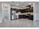 Modern kitchen featuring dark wood cabinetry, stainless steel appliances, and tile flooring at 538 Ylang Pl, Henderson, NV 89015