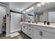 Modern bathroom featuring a double sink vanity, large mirror and a glass door shower at 7077 Sunland Hills Ave, Las Vegas, NV 89113