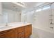 Bright bathroom features double sinks, wood cabinetry, and a shower-tub combination with tiled walls and natural light at 7464 Edgecove Ct, Las Vegas, NV 89139