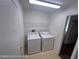 Functional laundry room with washer, dryer, and overhead storage shelving at 7464 Edgecove Ct, Las Vegas, NV 89139