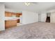 Open-concept living room with adjoining kitchen featuring wood cabinets and a breakfast bar, adjacent to carpeted stairs at 7464 Edgecove Ct, Las Vegas, NV 89139