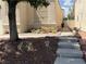 Quaint front yard with desert landscaping, pathway, and mature tree, leading to the home's entrance at 7620 Donald Nelson Ave, Las Vegas, NV 89131