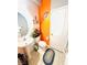Cozy half bath featuring a pedestal sink, oval mirror, and colorful orange accent wall at 8156 Blue Hope Diamond Ln, Las Vegas, NV 89139
