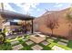 Backyard patio with pergola and dining table alongside a fire pit area, brick pavers, artificial turf, and landscaping at 8941 Indigo Rose St, Las Vegas, NV 89166