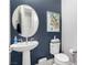 Modern half bathroom featuring a pedestal sink, round mirror, and stylish wall art at 8941 Indigo Rose St, Las Vegas, NV 89166