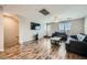 A modern living room with wood-look flooring, a ceiling fan, and black leather sofas at 9050 W Tropicana Ave # 1015, Las Vegas, NV 89147