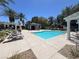 Community pool featuring lounge chairs, sun umbrellas, covered patio, set under blue skies and mature palm trees at 9116 Vista Greens Way # 104, Las Vegas, NV 89134