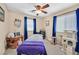 Bedroom features a ceiling fan, massage table, cat tree, and natural light from two windows with blue curtains at 9118 Mount Wilson St, Las Vegas, NV 89113