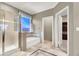 Bright bathroom with a glass-enclosed shower, soaking tub, and linen window for natural light and privacy at 93 Autumn Day St, Henderson, NV 89012