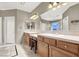 Well-lit bathroom featuring double sinks, ample counter space, wood cabinets, and a decorative tile floor at 93 Autumn Day St, Henderson, NV 89012