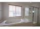 Bathroom view showcasing a soaking tub, glass-enclosed shower, and a window at 9312 Poseidon Valley Ave, Las Vegas, NV 89178