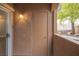 Neutral covered patio door with lantern fixture and stucco wall with mature tree view at 10291 Delta View Ct # 101, Las Vegas, NV 89129