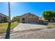 A bright single-story house featuring a large driveway, a two-car garage, and desert landscaping at 1441 Palm Dr, Laughlin, NV 89029