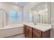Bright bathroom featuring double sinks, quartz countertops, soaking tub, and walk-in shower at 157 Sarabeth St, Las Vegas, NV 89138