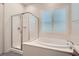 Bright bathroom featuring a soaking tub, walk-in shower, and plantation shutters at 157 Sarabeth St, Las Vegas, NV 89138
