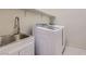 Well-lit laundry room featuring a utility sink with modern faucet and a new white side-by-side washer and dryer at 157 Sarabeth St, Las Vegas, NV 89138