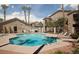 Community pool with lounge chairs, surrounded by lush landscaping and multi-story residential buildings on a sunny day at 2110 Los Feliz St # 1034, Las Vegas, NV 89156