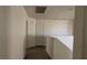 A second story hallway with white walls and gray laminate flooring leads to a door at 3021 New Journey Way, North Las Vegas, NV 89031
