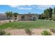 Expansive backyard showcasing a covered patio, green lawn, desert landscaping, and mature trees at 415 Emerald Cir, Henderson, NV 89002