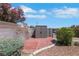 Storage shed on a tile patio with a block wall, surrounded by rock landscaping and foliage at 415 Emerald Cir, Henderson, NV 89002