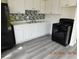 Modern kitchen with white cabinets, stainless appliances, mosaic backsplash, and gray wood-look floors at 4382 Pinegrove St, Las Vegas, NV 89147