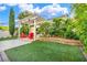 Manicured backyard with a pergola, artificial grass, garden beds, and red Adirondack chairs at 5553 Coral Gate St, Las Vegas, NV 89148