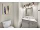 Clean, neutral half-bath with grey vanity, chrome fixtures, and stylish feather wall art at 5553 Coral Gate St, Las Vegas, NV 89148