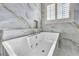 Bright bathroom featuring a soaking tub with marble tile surround, jacuzzi jets and shuttered window at 5553 Coral Gate St, Las Vegas, NV 89148