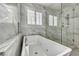 Modern bathroom featuring a soaking tub with jacuzzi jets, a glass shower stall and marble tile surround at 5553 Coral Gate St, Las Vegas, NV 89148