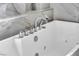 Close-up of a soaking tub featuring marble tile surround, silver hardware, and jacuzzi jets at 5553 Coral Gate St, Las Vegas, NV 89148