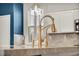 Close-up of kitchen with granite countertop and a gold faucet with matching hardware at 5553 Coral Gate St, Las Vegas, NV 89148