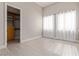 Bright bedroom with tile floors, two windows, and a walk-in closet with custom shelves and drawers at 5576 Buena Martina Way, Las Vegas, NV 89141