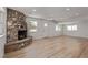 Open-concept living room with a stone fireplace, bright white walls, and new light wood flooring at 659 D Ave, Boulder City, NV 89005
