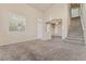 Bright living room boasts soaring ceilings, neutral-colored carpet, and a staircase leading upstairs at 6804 Tropicaire St, Las Vegas, NV 89149