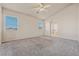 Spacious main bedroom with neutral carpeting, two windows, ceiling fan, and ensuite bath access at 6804 Tropicaire St, Las Vegas, NV 89149