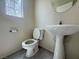 Cozy half bath with modern toilet, pedestal sink, and small window for ample natural light at 7469 Margollini St, Las Vegas, NV 89148