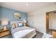 Cozy bedroom with a blue accent wall, round mirror, bedside tables, and ample natural light at 7925 Pandora Sky St # 392, Las Vegas, NV 89084