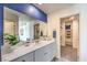 Bathroom featuring dual sinks, a blue accent wall, and a closet with built-in shelving at 7935 Pandora Sky St # 393, North Las Vegas, NV 89084