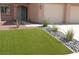 Lush artificial turf with decorative rock landscaping leading to the home's entrance and a three-car garage at 825 Cornerstone Pl, North Las Vegas, NV 89031