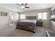 Comfortable main bedroom featuring neutral colors, ceiling fan, large window, and access to the main bath at 8925 Kenzie Cove St, Las Vegas, NV 89131