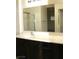 Bright bathroom features a sink with a dark vanity, a large mirror and a walk-in shower with glass doors at 9402 Crimson Sky St, Las Vegas, NV 89178