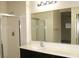 Bright bathroom features a sink with a dark vanity, a large mirror and a walk-in shower with glass doors at 9402 Crimson Sky St, Las Vegas, NV 89178