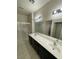 Bright bathroom features double sinks, a dark vanity, a large mirror and a walk-in shower with glass doors at 9402 Crimson Sky St, Las Vegas, NV 89178