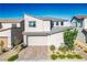 Contemporary two-story home featuring a brick driveway, a two-car garage, and a modern design, set under a clear blue sky at 9476 Lunar Phase St, Las Vegas, NV 89143