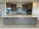 Open concept kitchen with large island, gray cabinetry, stainless appliances and tile backsplash at 9476 Lunar Phase St, Las Vegas, NV 89143