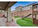 Inviting backyard featuring artificial turf, patio seating, and a charming playhouse with a slide at 9835 Fox Estate St, Las Vegas, NV 89141
