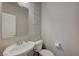 A half bath with a pedestal sink, toilet, decorative art and a clean, minimalist design at 9835 Fox Estate St, Las Vegas, NV 89141